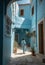 A woman walks along a narrow paved street between buildings on a sunny day, ai artwork