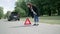 A woman walks along the side of the road and installs red triangular warning signal. Emergency stop sign on the road closeup.