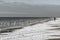 A woman walks along a snowy beach