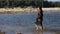 Woman walks barefoot on shallow water on beach