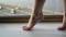 Woman walks barefoot on window sill on tiptoes against the of a panoramic window