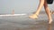 A woman walks and dances on the beach. Female legs jump on the sea waves