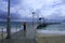 A woman walks on Jurien Bay Jetty in Western Australia during low clouds of incomimg storm.