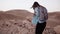 Woman walks near mountain drop. Slow motion. Young tourist girl on desert canyon edge. Hair blowing in the wind. Israel.