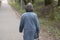 A woman walks through the park. An elderly woman alone in the street