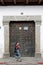 Woman walks past antique doorway in Antigua, Guatemala.