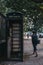 Woman walks past black phone box on Euston Road in London, UK.