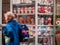 A woman walks past a small street shop. Showcase with the heads of mannequins. Sale of hats, stockings and socks and other small