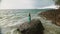 Woman walks on rock of sea reef stone, stormy cloudy ocean. Blue swimsuit dress tunic. Concept rest, tropical resort