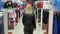 Woman walks between the rows of clothes in the store and looks around.