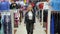 Woman walks between the rows of clothes in the store and looks around.