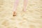woman walks on sand on beach, leaving footprints. Legs close up. female feet on golden sand