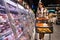 Woman walks with a shopping cart between the rows of a grocery supermarket.