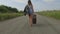 Woman walks with a suitcase on the road
