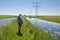 Woman walks through the typical flat Dutch landscape of grass an