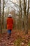 Woman in warm cardigan and hat walking through autumnal woodland