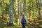 A woman in warm clothes enjoys a walk in a pine forest