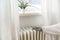 Woman with warm clothes and gloves puts her hand on an old heater to feel the temperature, saving energy due to inflation and