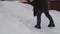 A woman in a warm coat with a shovel removes snow after a snowfall in the yard of her house