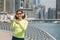Woman was running along Dubai Marina embankment and listens to music with headphones and shows the white screen of her