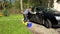 Woman wash black car with soapy sponge.