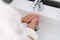 Woman washes hands in cool water in bathroom closeup