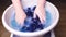 Woman washes with her hands blue men`s panties in a basin, knitted underwear, clean clothes concept, scandal in the Russian