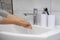 A woman washes her hands under a stream of water, selective focus. Modern bathroom interior