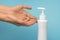 Woman washes her hands using liquid soap on a blue background. Girl uses liquid disinfectant to protect against COVID-19.