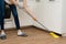 A woman washes underfloor heating in her house. Wash dirt from under the kitchen cabinet