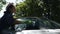 A woman washes the windshield of a car with a soapy sponge in the yard of her house in summer