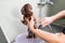 Woman washing brown mini toy poodle in grooming salon.