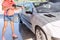 Woman washing car with pressure washer at self-service car wash station