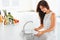 Woman washing a cup in white kitchen. Vegetables on the backgrou