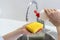 Woman washing dishware, pouring soap at sponge, standing on kitchen