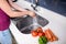 Woman washing hands at kitchen sink