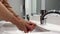 Woman washing her hands under running water from the Water faucet. Woman washes soap suds from her hands under running