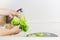 Woman washing lettuce and fruit in kitchen sink with running water.