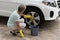 Woman washing the wheel of a white saloon car