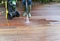 Woman washing wooden terrace with high pressure water