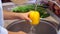 Woman washing yellow pepper in kitchen. Homemade food concept. Slow motion.