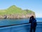 Woman watching birds with binoculars on ferry boat to Heimaey, Westman Islands, Iceland.