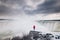 Woman watching Niagara falls from a snowy ledge