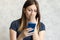 Woman watching shocking video online on her mobile phone. Young girl looking at phone seeing bad news or photos. Girl pleasantly