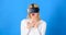 Woman watching virtual reality vision. Woman using VR device. Woman wearing virtual reality goggles in blue background