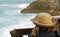 A Woman Watching Waves Crash over rocks on Beach