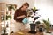 Woman watering Croton plant at home. Engaging hobby