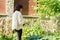 Woman watering flowerbeds with a hose in garden