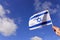 Woman wave flag of Israel against blue sky