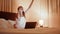 Woman waving with fan of euro while sitting on bed